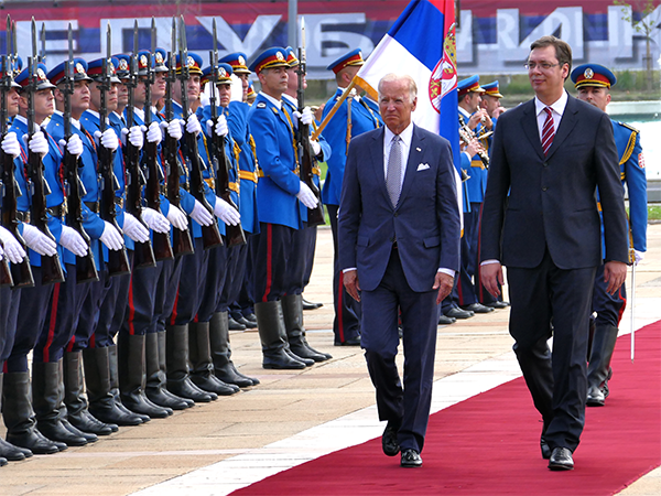 A photo of President Biden walking along a line of soldiers standing at attention.