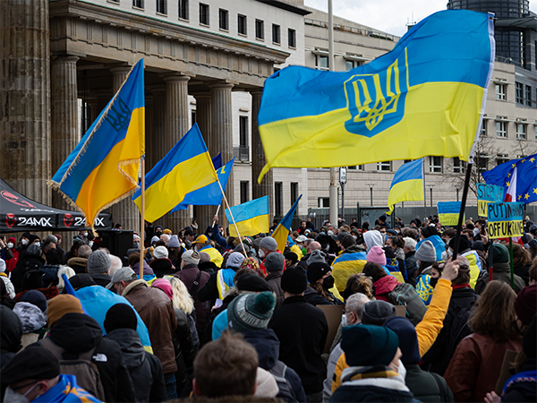 A crowd of protestors, several holding Ukrainian flags.