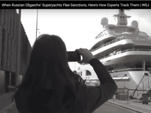 A photo of a woman taking a photo of a yacht.