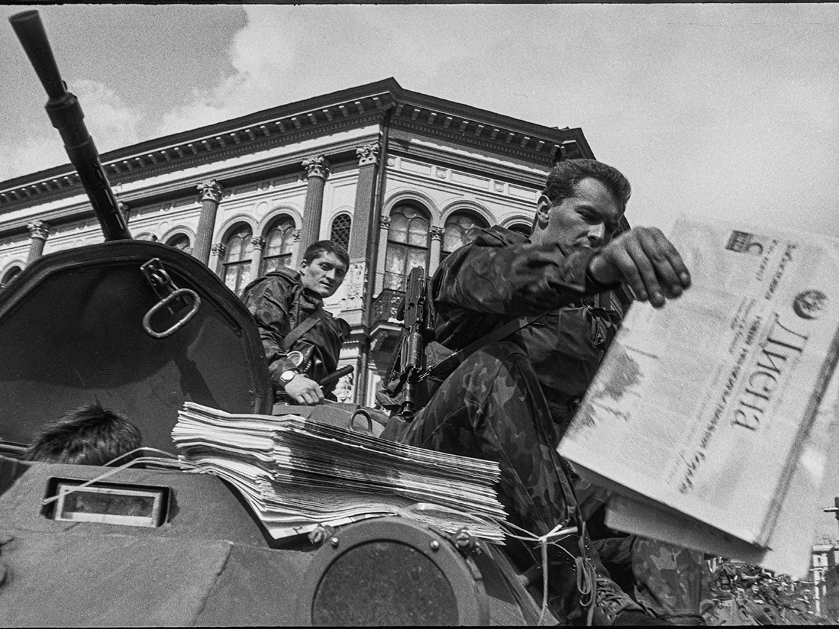 article p25 diena article Image of soldiers handing out "Diena"